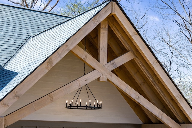 details featuring a high end roof, roof with shingles, and a notable chandelier