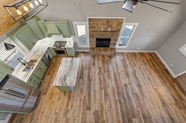 living room featuring baseboards, a fireplace, a ceiling fan, and wood finished floors