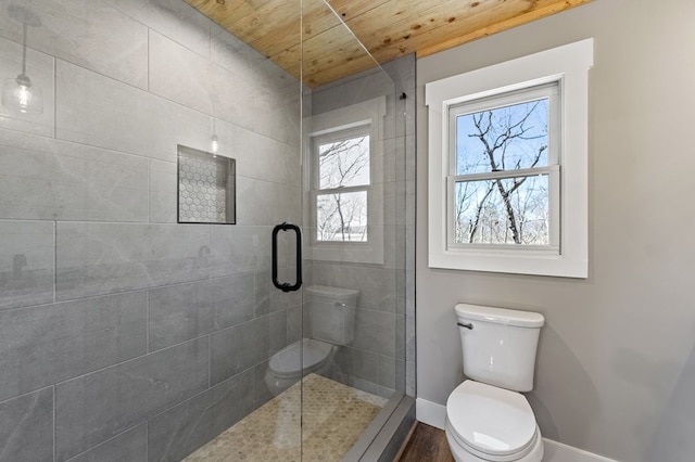 full bathroom with wooden ceiling, a tile shower, toilet, and baseboards