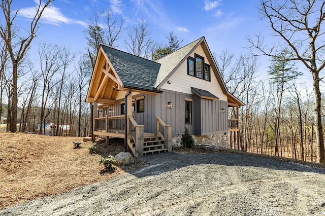 rustic home with board and batten siding, roof with shingles, and driveway