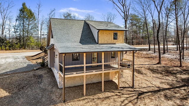 back of house with a shingled roof, driveway, and board and batten siding