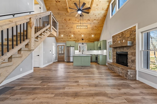 unfurnished living room featuring a healthy amount of sunlight, wood finished floors, and a stone fireplace