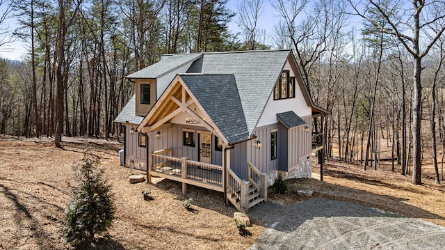 view of front of home featuring roof with shingles, board and batten siding, and driveway