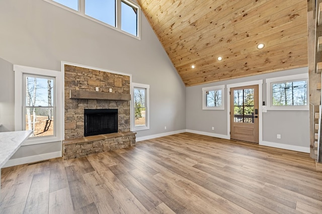 unfurnished living room featuring a stone fireplace, wooden ceiling, wood finished floors, and baseboards