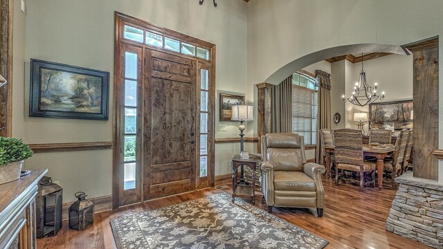 living area featuring a chandelier, ornamental molding, wood finished floors, and a towering ceiling