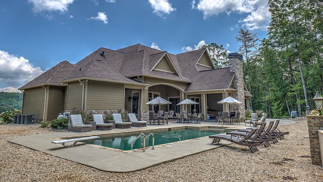 view of home's exterior with a garage, stone siding, a shingled roof, and a chimney