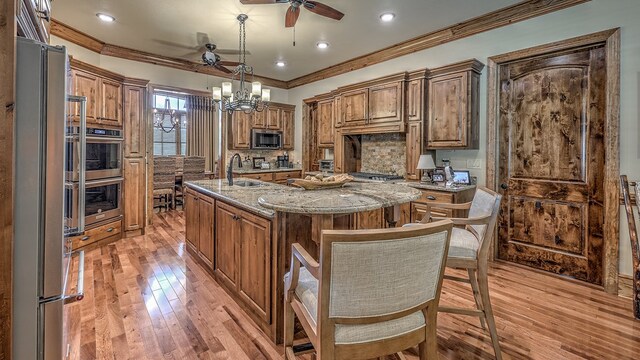 kitchen featuring a kitchen island with sink, a sink, appliances with stainless steel finishes, decorative backsplash, and crown molding