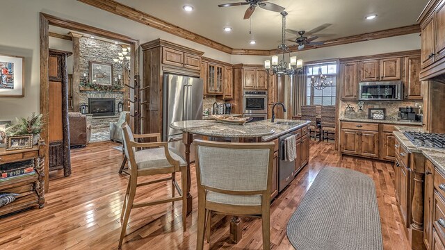 kitchen featuring a kitchen island with sink, appliances with stainless steel finishes, brown cabinets, and a sink