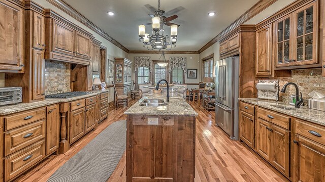 kitchen featuring brown cabinets, a kitchen island with sink, stainless steel appliances, and a sink