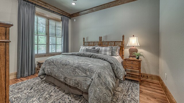 bedroom with baseboards, wood finished floors, and crown molding