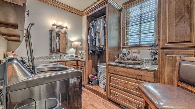 clothes washing area featuring light wood-type flooring, laundry area, and crown molding