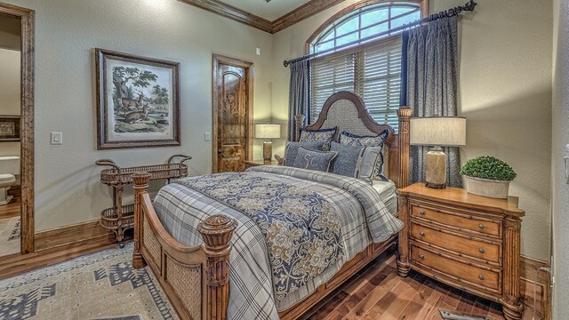 bedroom featuring ornamental molding, wood-type flooring, a textured wall, and baseboards