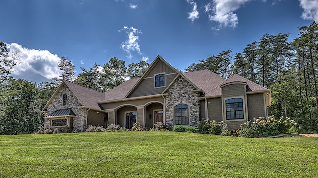 view of front of property with stone siding, a front lawn, and roof with shingles