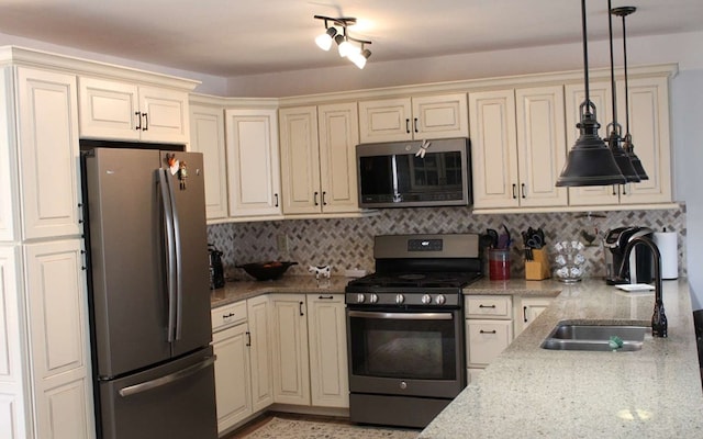 kitchen featuring sink, hanging light fixtures, cream cabinetry, appliances with stainless steel finishes, and light stone countertops