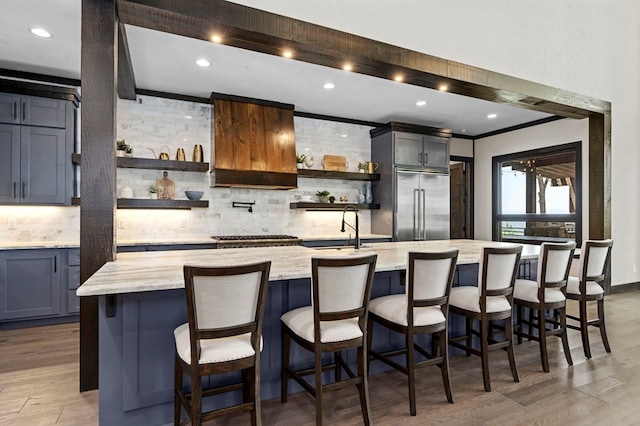 kitchen featuring a large island, light stone counters, a breakfast bar, and built in fridge