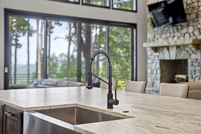 kitchen featuring a stone fireplace, sink, and plenty of natural light