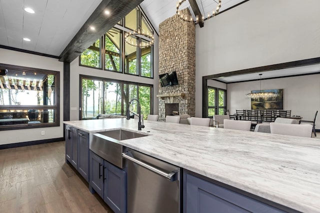 kitchen with a fireplace, hanging light fixtures, stainless steel dishwasher, high vaulted ceiling, and dark hardwood / wood-style floors