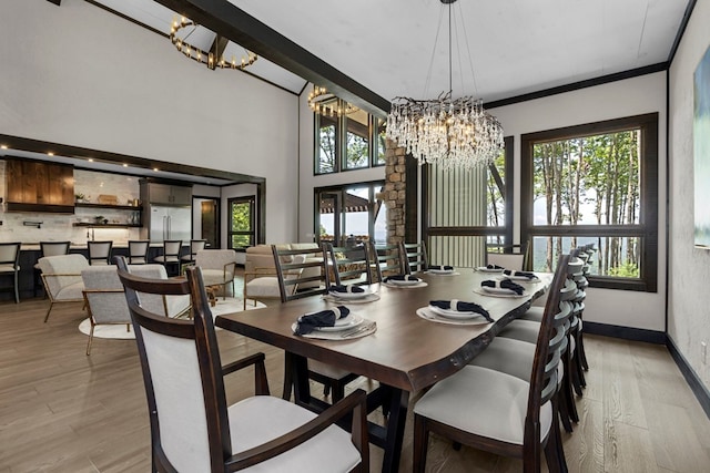 dining area with a healthy amount of sunlight, ornamental molding, a high ceiling, and light wood-type flooring