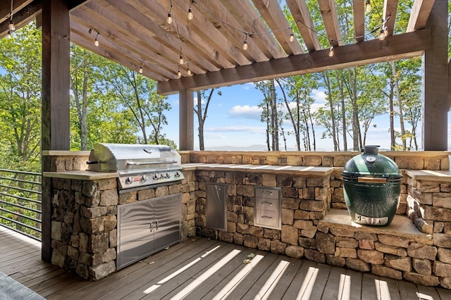 wooden deck featuring a pergola, grilling area, and exterior kitchen