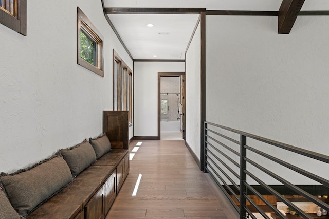 hall featuring beam ceiling, ornamental molding, and wood-type flooring