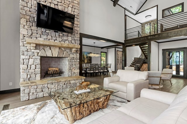 living room with an inviting chandelier, hardwood / wood-style floors, a fireplace, and high vaulted ceiling