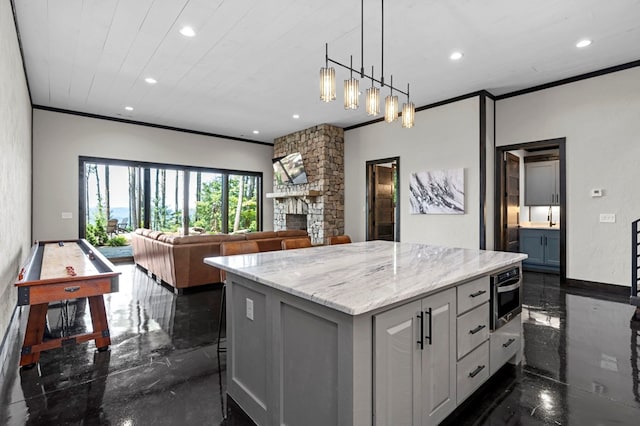 kitchen featuring light stone countertops, a kitchen island, a fireplace, white cabinets, and crown molding