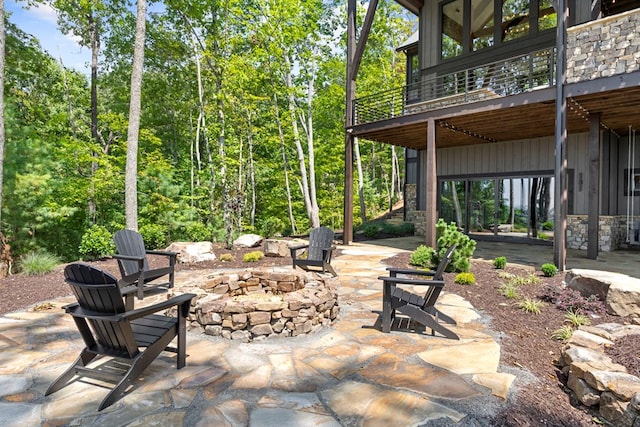 view of patio with a balcony and an outdoor fire pit