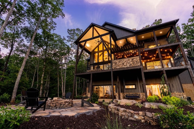 back house at dusk featuring a patio, an outdoor fire pit, and a balcony