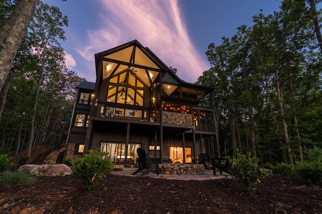 back house at dusk featuring a patio