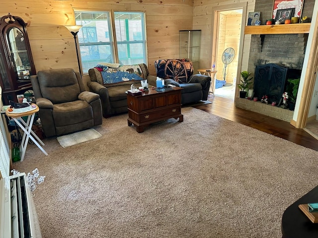 living room with hardwood / wood-style flooring, wooden walls, and a brick fireplace