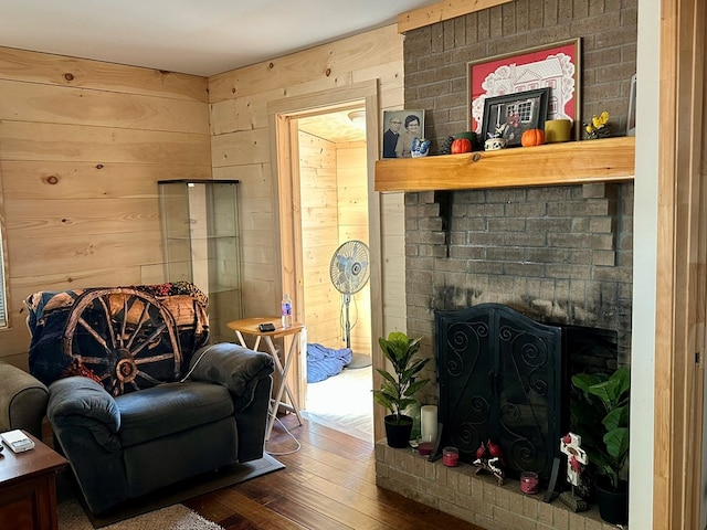 living room featuring wood walls, dark hardwood / wood-style flooring, and a brick fireplace