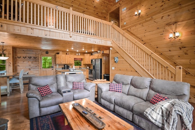 living room featuring a towering ceiling, wood-type flooring, and wood walls