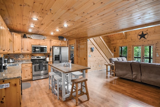 kitchen with sink, light stone counters, wooden ceiling, wooden walls, and stainless steel appliances