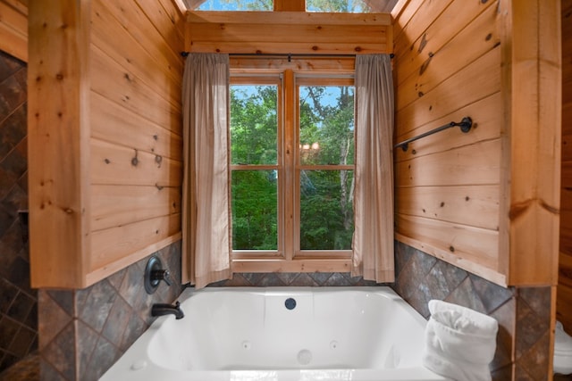 bathroom featuring a washtub, wooden walls, and a skylight