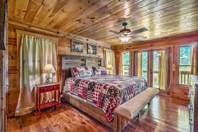 bedroom featuring wood walls, wood-type flooring, access to exterior, ceiling fan, and wood ceiling