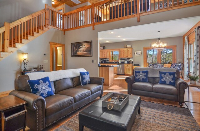 living area featuring wood finished floors, stairway, a chandelier, a high ceiling, and recessed lighting
