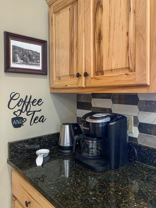 kitchen view of tasteful backsplash, light brown cabinets, and dark stone counters