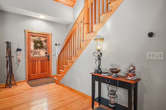 foyer entrance featuring stairs, wood finished floors, and baseboards