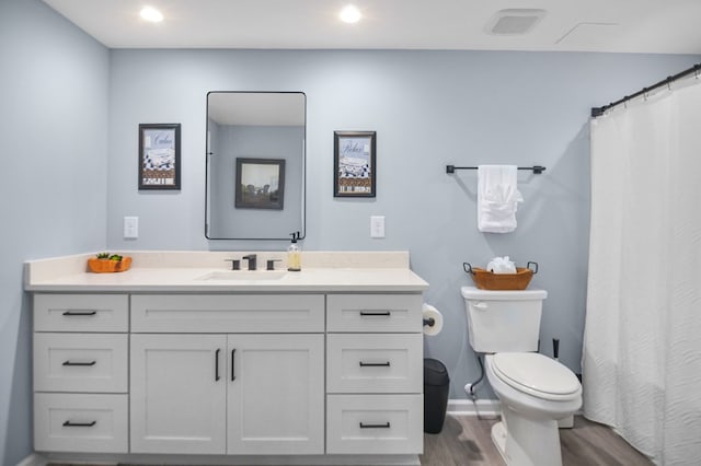 bathroom with wood finished floors, toilet, vanity, recessed lighting, and baseboards