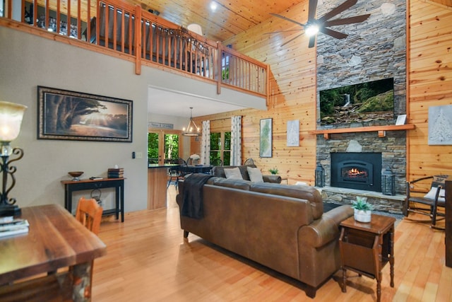 living room with ceiling fan, wood finished floors, a fireplace, wooden ceiling, and a high ceiling