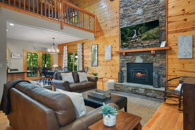 living area with a stone fireplace, wood walls, wood finished floors, a towering ceiling, and recessed lighting