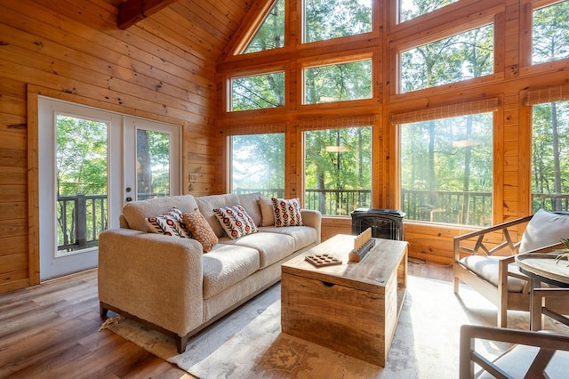 living room featuring french doors, wooden walls, a healthy amount of sunlight, and light wood finished floors