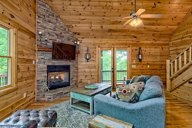 living room featuring a stone fireplace, plenty of natural light, and wooden ceiling