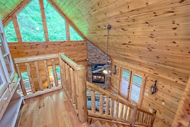 stairs with hardwood / wood-style floors, wood walls, wooden ceiling, and a fireplace