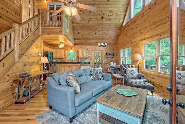 living room with a wealth of natural light, light wood-type flooring, sink, and high vaulted ceiling