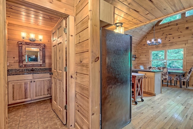 bathroom with lofted ceiling, an inviting chandelier, wooden ceiling, and wood walls