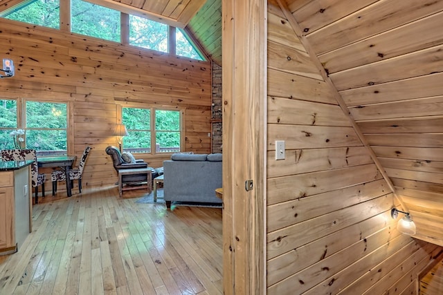 interior space with lofted ceiling, light wood-type flooring, wooden ceiling, and wood walls