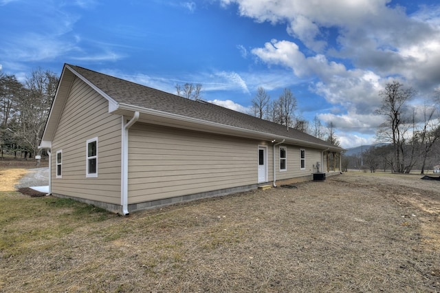 view of side of property with cooling unit and a lawn