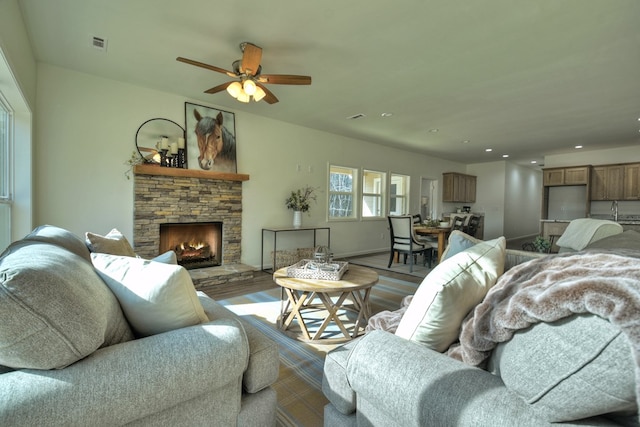 living room with sink, a stone fireplace, and hardwood / wood-style floors