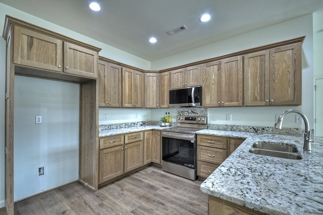 kitchen featuring sink, stainless steel appliances, light hardwood / wood-style floors, and light stone countertops